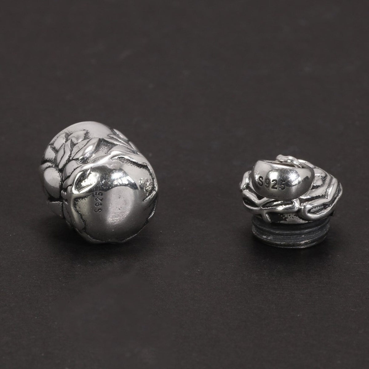 A close-up photograph showing the two separated locket pieces (main body and lid) resting next to each other, highlighting their intricate carved details and shapes