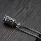 A close-up side view of the closed lotus locket pendant attached to its chain, showcasing the detailed carvings and chain texture against a dark wood background.