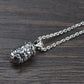 An angled view of the closed silver lotus locket pendant attached to its matching chain, resting on a dark wooden surface