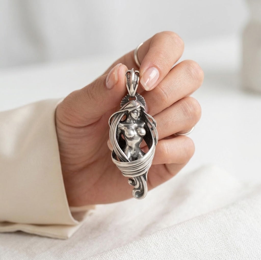 Close up shot of handcrafted silver female body pendant with antiqued polish in woman hand