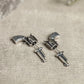 Detailed close up of 3d silver gun earrings on stone