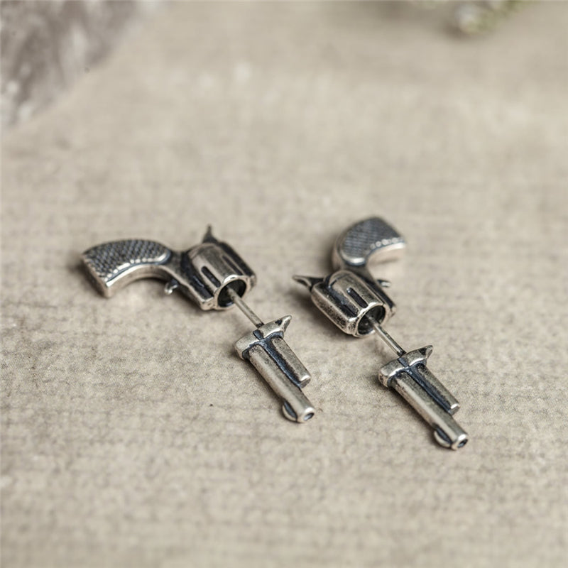 Detailed close up of 3d silver gun earrings on stone