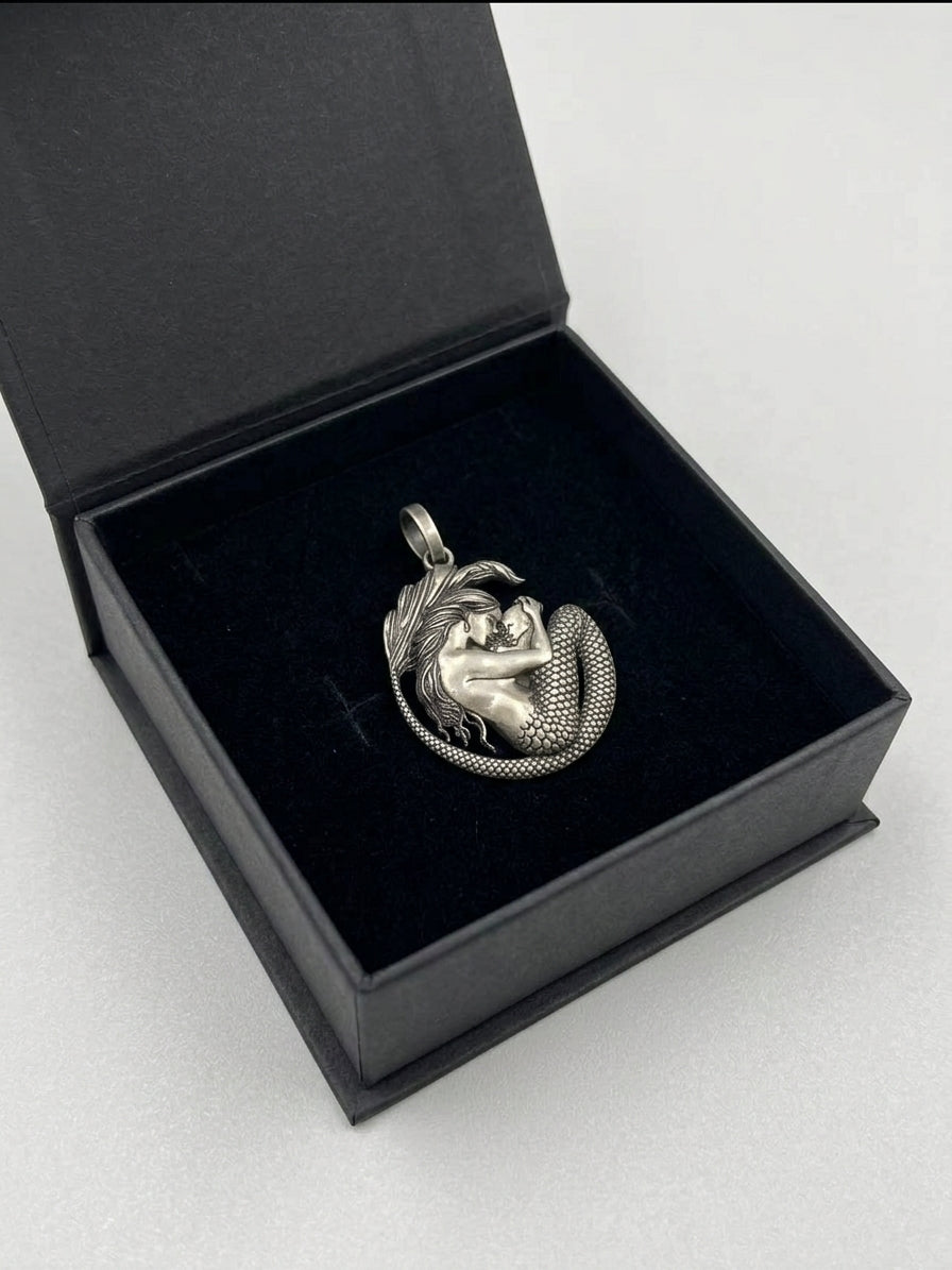 Detailed oxidized silver mermaid and child charm inside black jewelry box