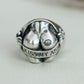 Front-facing product shot of the silver sculpted butt signet ring on a light neutral background, displaying the "KISS MY ASS" engraved banner and lip mark accent