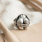 Lifestyle product shot showing the silver ring sitting tucked inside the pocket of a beige canvas handbag