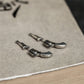 Pair of silver pistol stud earrings resting on textured vintage wooden surface