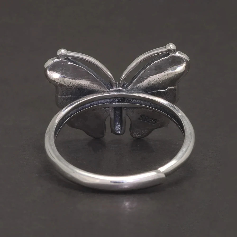 Silver butterfly ring on a dark background back side