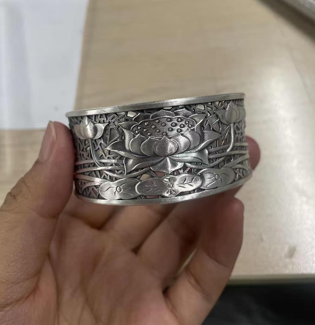 Woman holding a 999 silver lotus bangle in her hand