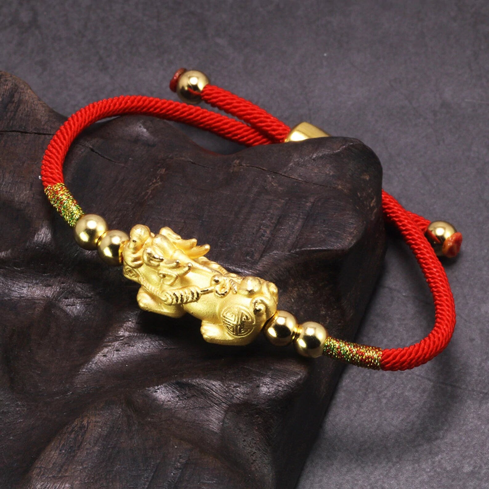 gold pixiu bracelet on dark background closeup side angle