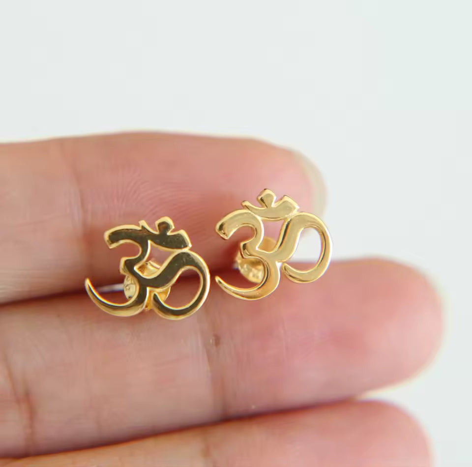 gold plated om symbol studs held in hand detailed view
