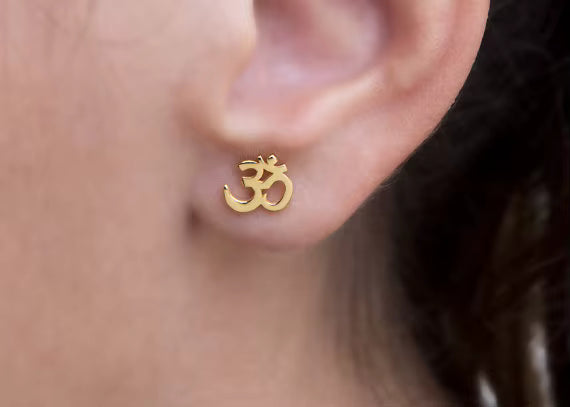 om stud earrings in gold on ear