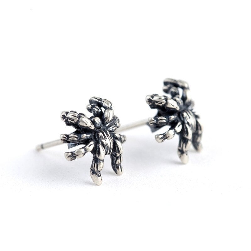 silver spider earrings on white background side view