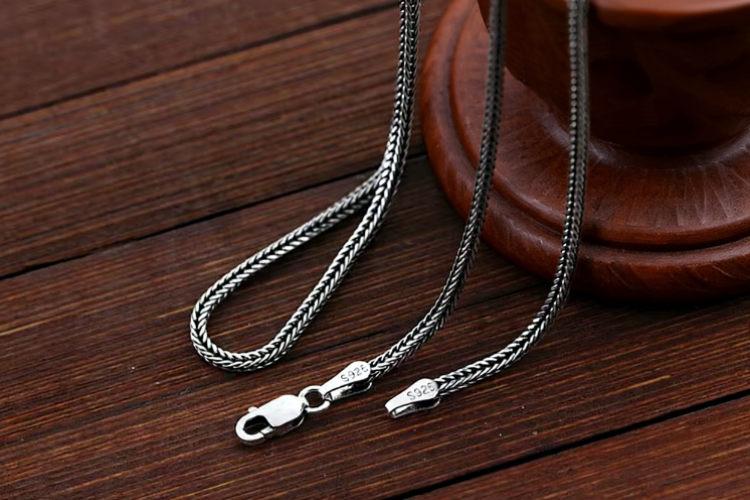 silver wheat chain necklace displayed on wood