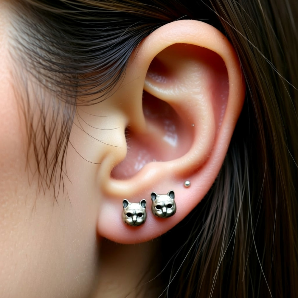small cat earrings worn on ear lobe close up
