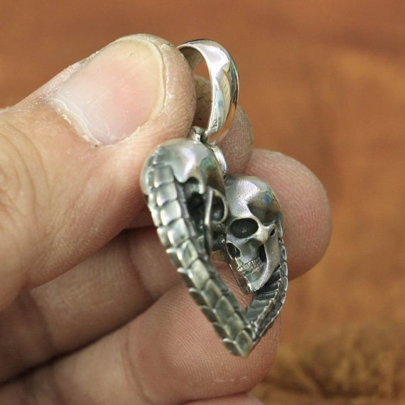 sterling silver skull heart necklace held in hand showing details