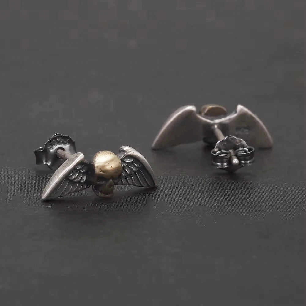 sterling silver skull wing earrings close up on dark background